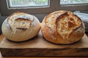 Side-by-side comparison of two sourdough boules on a wooden board — one pale beige and dull, one deep golden brown with a crisp crackled crust, natural window light, rustic farmhouse setting, food photography style.